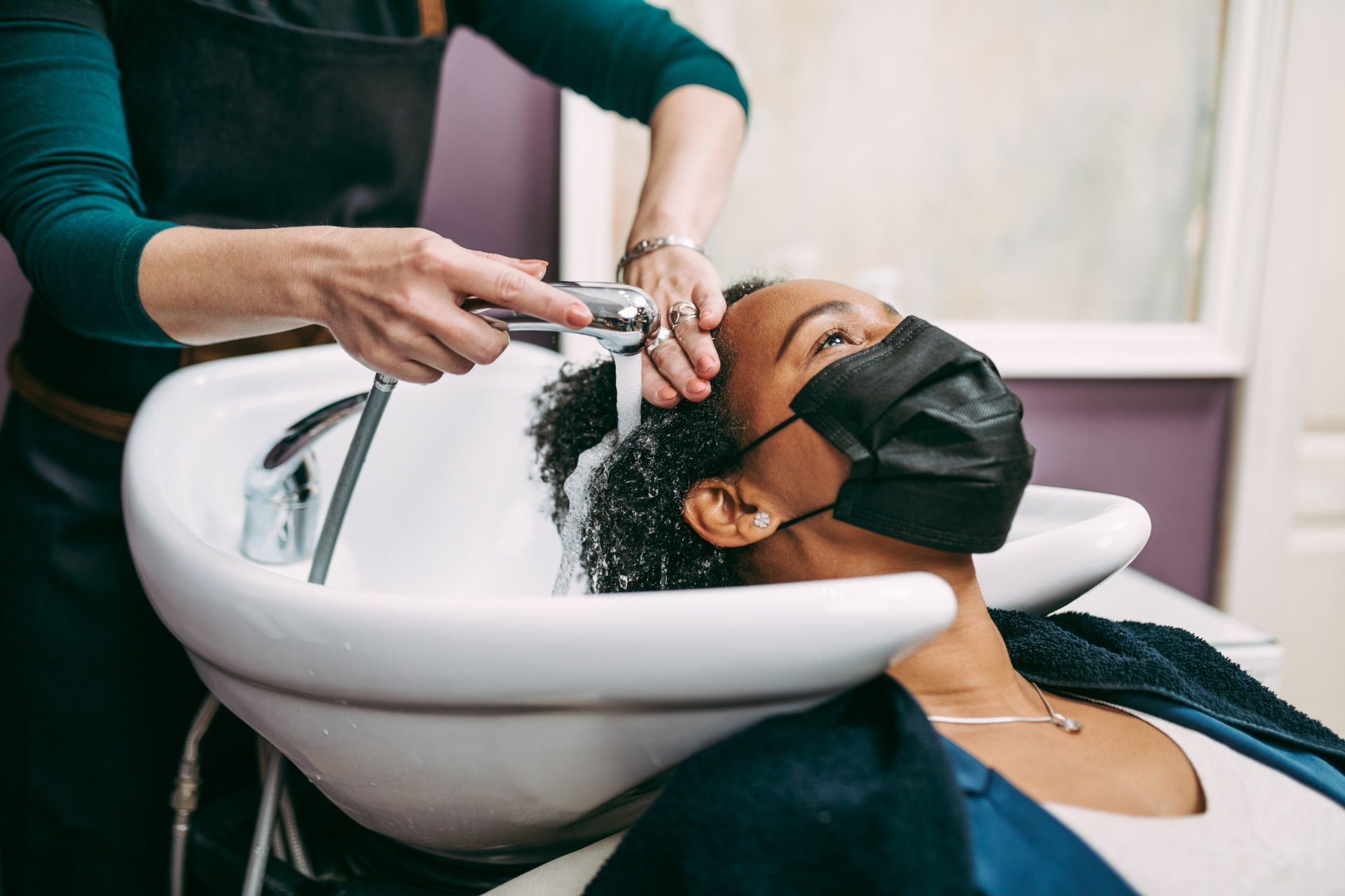 A woman with natural hair getting her hair washed at the salon